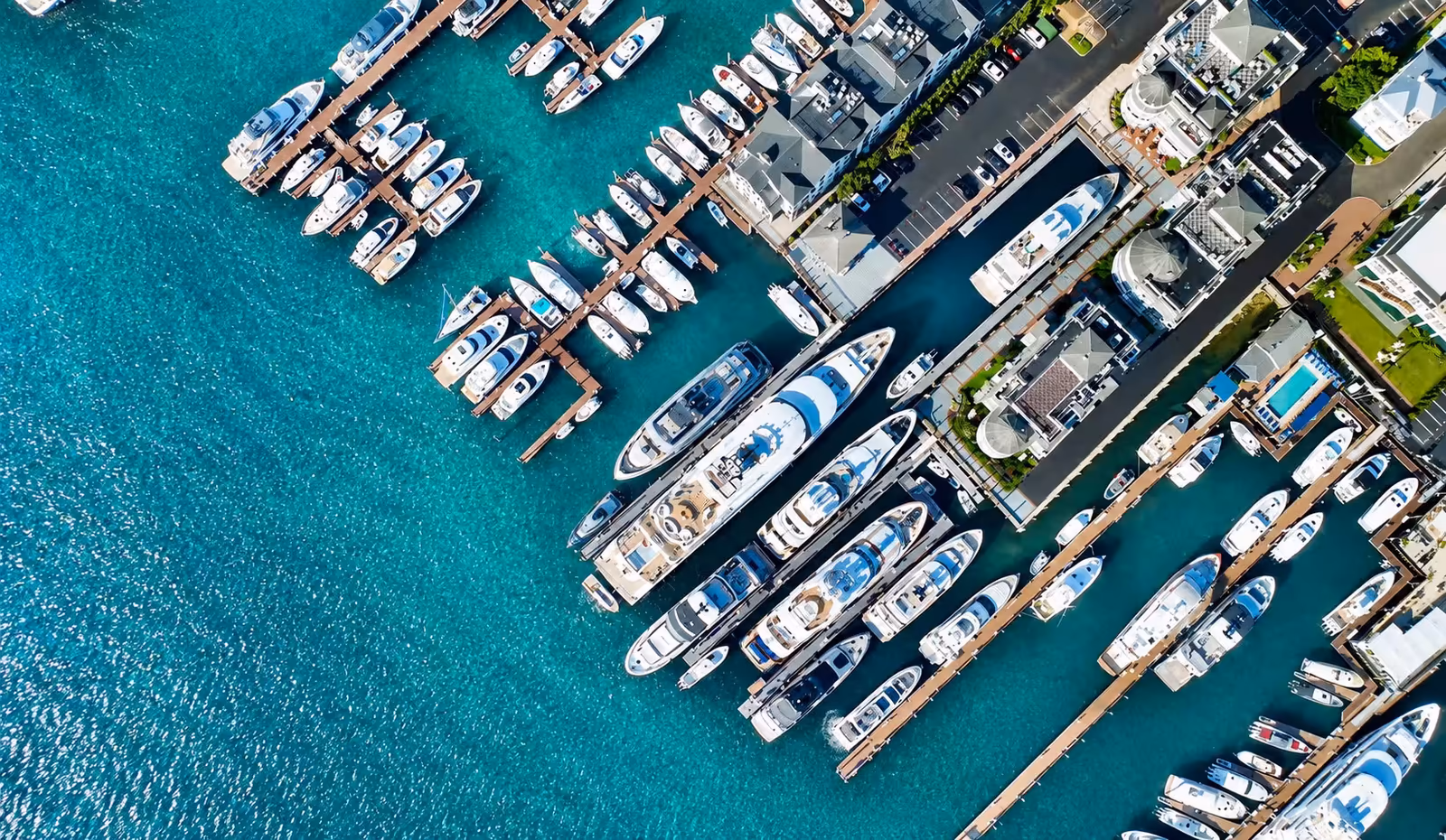 An overhead view of a busy marina, yachts and tenders moored along its docks.